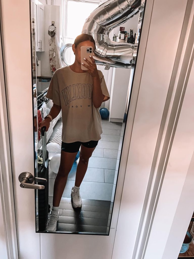 Tan Brooklyn NY graphic tee, black biker shorts, and white sneakers