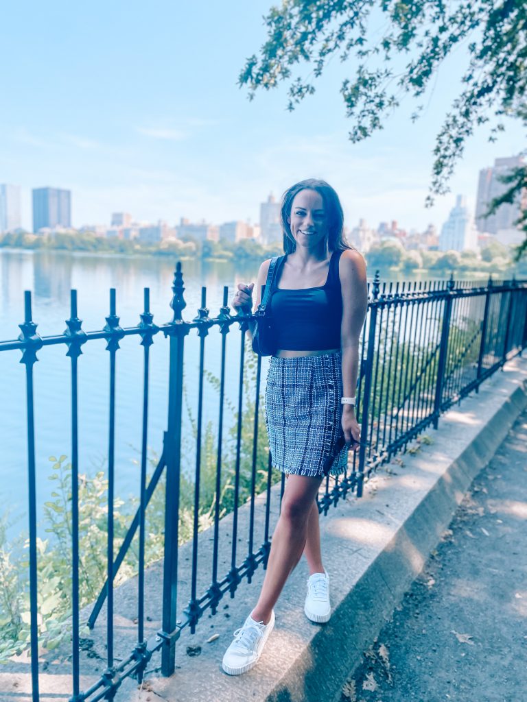 Standing at Central Park Skyline in black tank, plaid skirt, and white sneakers