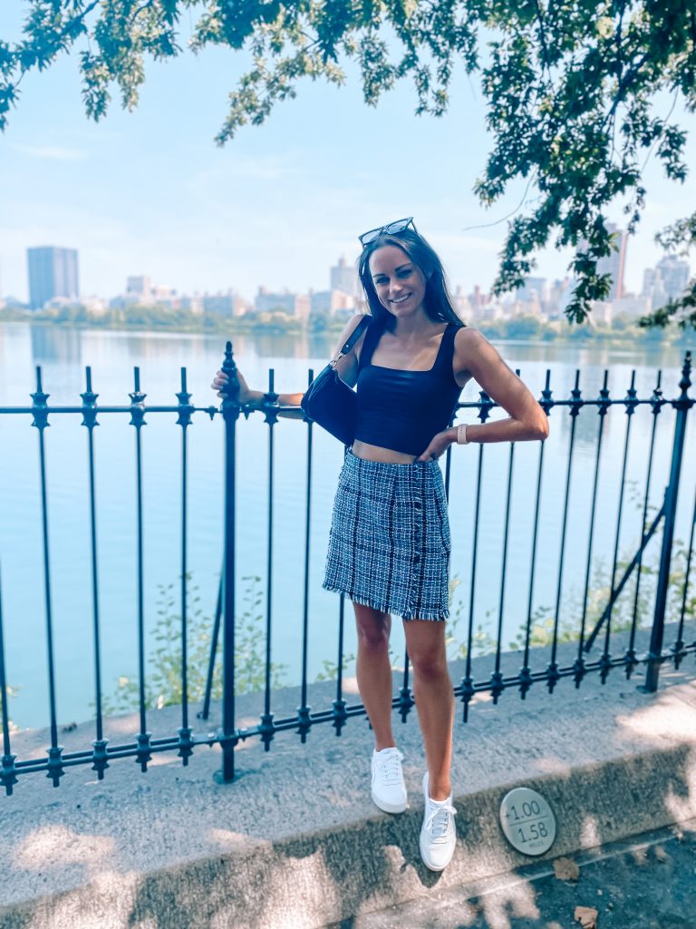 Standing at Central Park Skyline in black tank, plaid skirt, and white sneakers